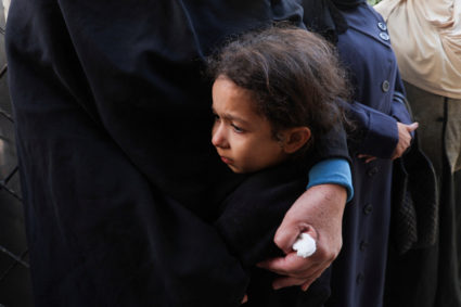 A child reacts while holding a person near the bodies of Palestinians killed in Israeli strikes at a hospital in Rafah