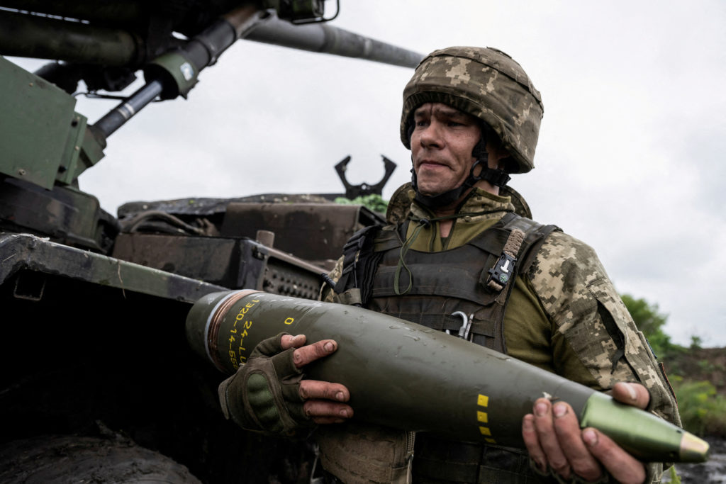 FILE PHOTO: Ukrainian service member carries a shell for a Caesar self-propelled howitzer before firing towards Russian tr...