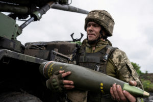 FILE PHOTO: Ukrainian service member carries a shell for a Caesar self-propelled howitzer before firing towards Russian tr...