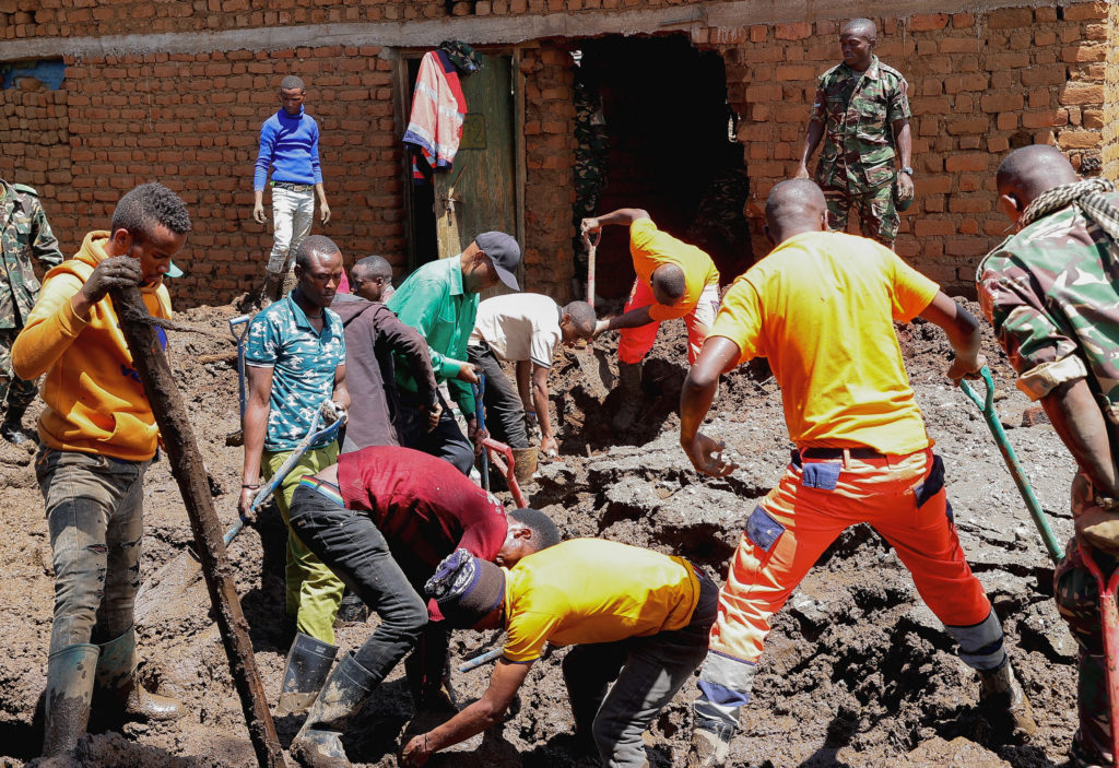 Members of the Tanzania Defense Forces and rescuers search for the bodies of people killed following flash floods and land...