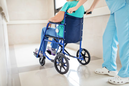 Low section of nurse pushing patient on wheelchair