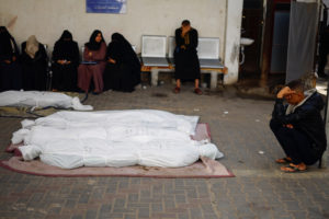 People mourn next to bodies of Palestinians killed in Israeli strikes, in Rafah
