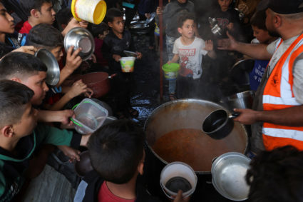 Palestinians gather to get their share of charity food offered by volunteers, amid food shortages, in Rafah