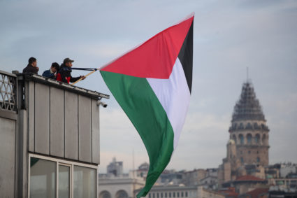 A demonstrator waves a Palestinian flag over the Galata Bridge in solidarity with Palestinians, amid the ongoing conflict between Israel and the Palestinian Islamist group Hamas, following the first morning prayer of the New Year in Istanbul, Turkey January 1, 2024. Photo by Dilara Senkaya/REUTERS