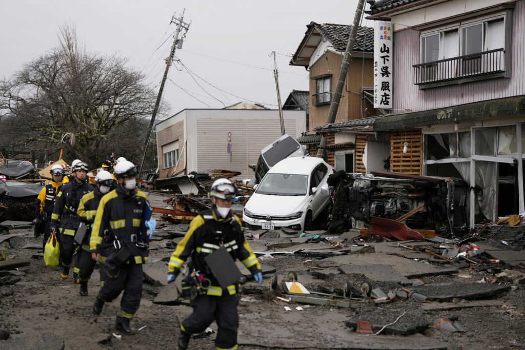 Firefighters conduct search and rescue operations at a tsunami-devastated residential area in Suzu