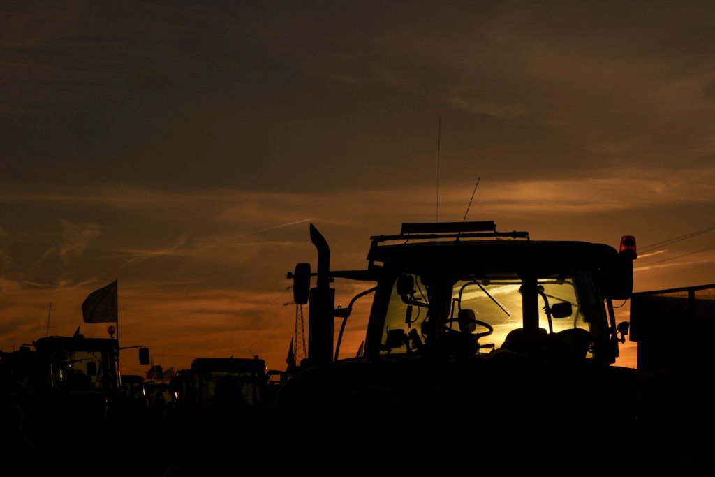 Farm vehicles are silhouetted during sunset as French farmers protest over price pressures, taxes and green regulation, si...