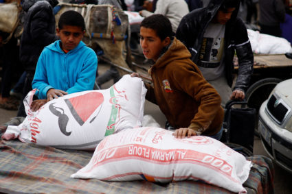 Palestinians gather to receive bags of flour distributed by UNRWA, in Rafah