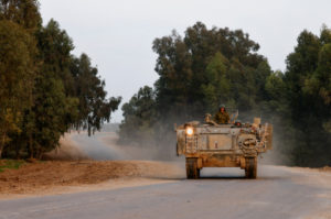 Israeli armoured personnel carrier (APC) maneuvers on a road outside the border with central Gaza, in southern Israel