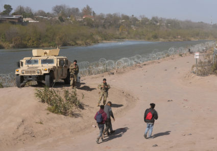 A group of migrants from Venezuela walk along the banks of the Rio Grande