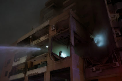 Water is sprayed on a damaged building at the site of an explosion, in what security sources say is an Israeli drone strik...