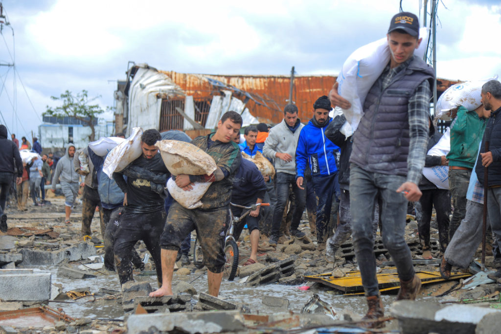 Palestinians carry bags of flour they grabbed from an aid truck near an Israeli checkpoint, in Gaza City