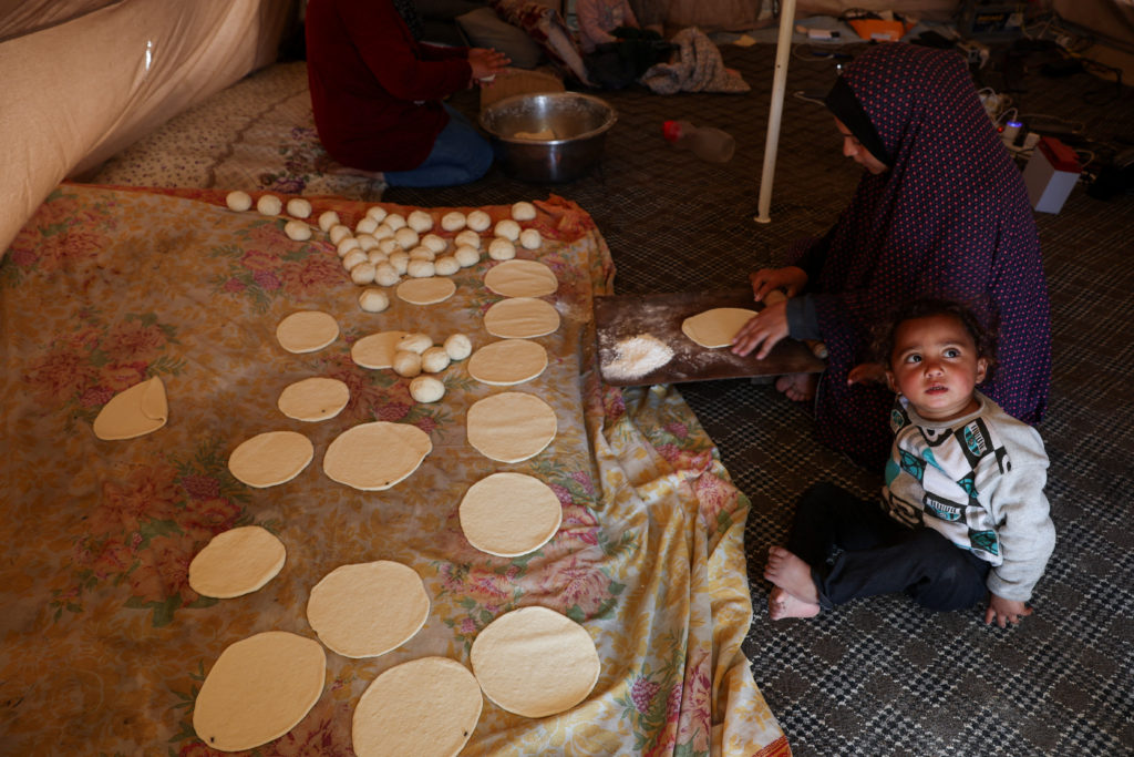 Displaced Palestinians who fled their houses due to Israeli strikes, shelter at a tent camp in Rafah