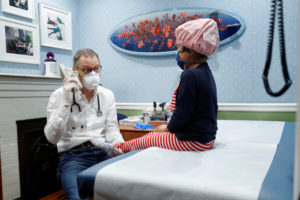 Dr Greg Gulbransen uses a girl's shoe as a phone to cheer her up at his pediatric practice in Oyster Bay