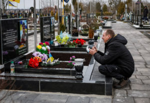 A man reacts as she visits the grave of his relative, a killed Ukrainian defender, on the day of the second anniversary of...