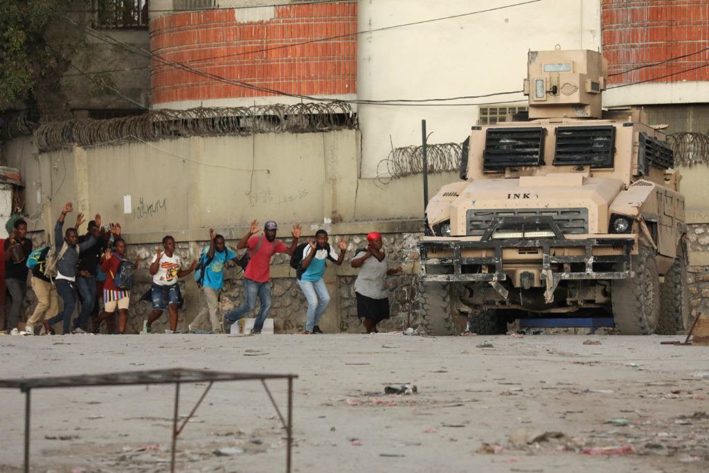 People move away from an area where police confront armed gangs after prominent gang leader Jimmy Cherizier called for Hai...