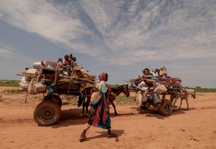 FILE PHOTO: A Sudanese woman, who fled the conflict in Murnei in Sudan's Darfur region, walks beside carts carrying her family belongings upon crossing the border between Sudan and Chad in Adre, Chad August 2, 2023. Photo by Zohra Bensemra/Reuters