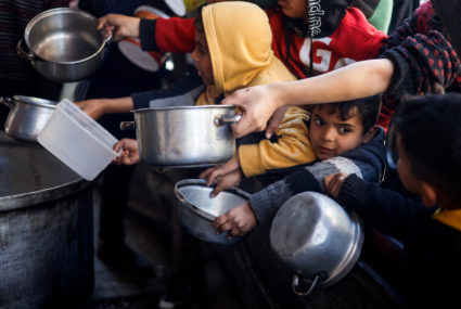 Palestinian children wait to receive food cooked by a charity kitchen amid shortages of food supplies, in Rafah