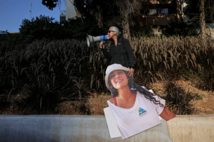 A woman uses a megaphone as she holds a cutout picture of hostage Emily Damari, as to protest for the return of female hos...