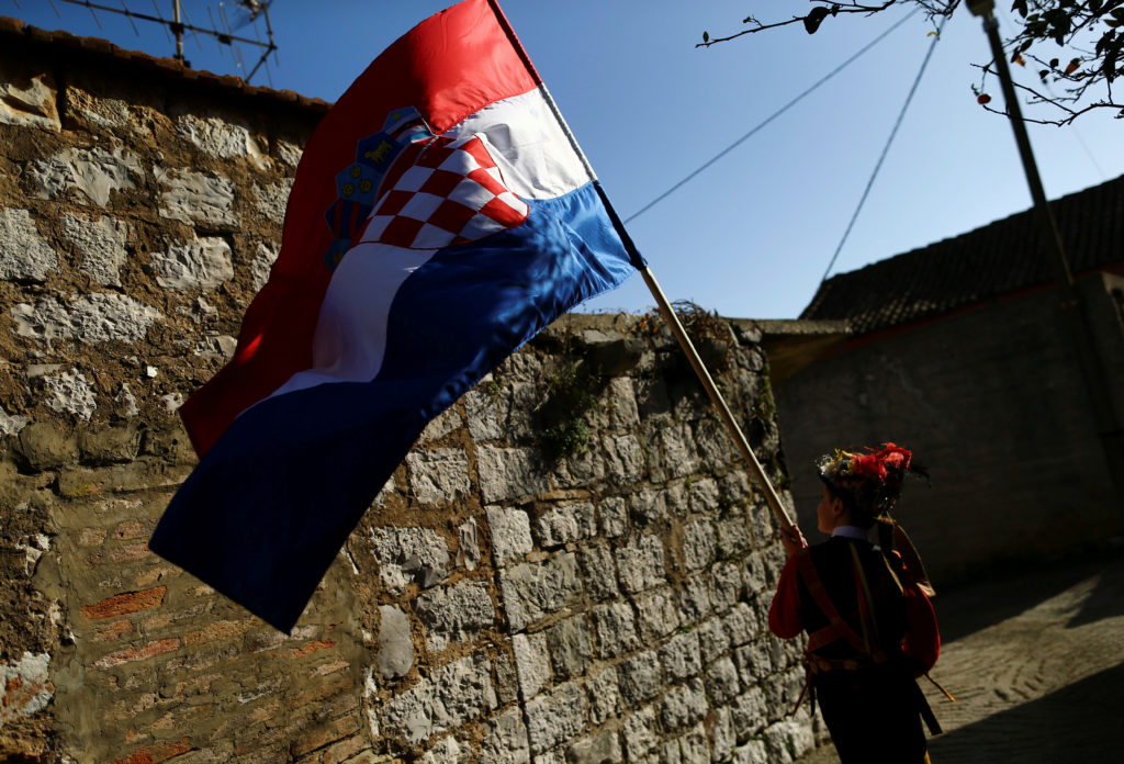 A boy dressed in a traditional costume walks as he holds a national flag during the "Poklad" in Lastovo