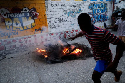 FILE PHOTO: Men run next to a pile of burning mattresses and the remains of the motorcycle of suspected gang leader Makandal who was killed and set on fire by local residents, amid an escalation in gang violence, in Port-au-Prince, Haiti March 20, 2024. Photo by Ralph Tedy Erol/Reuters