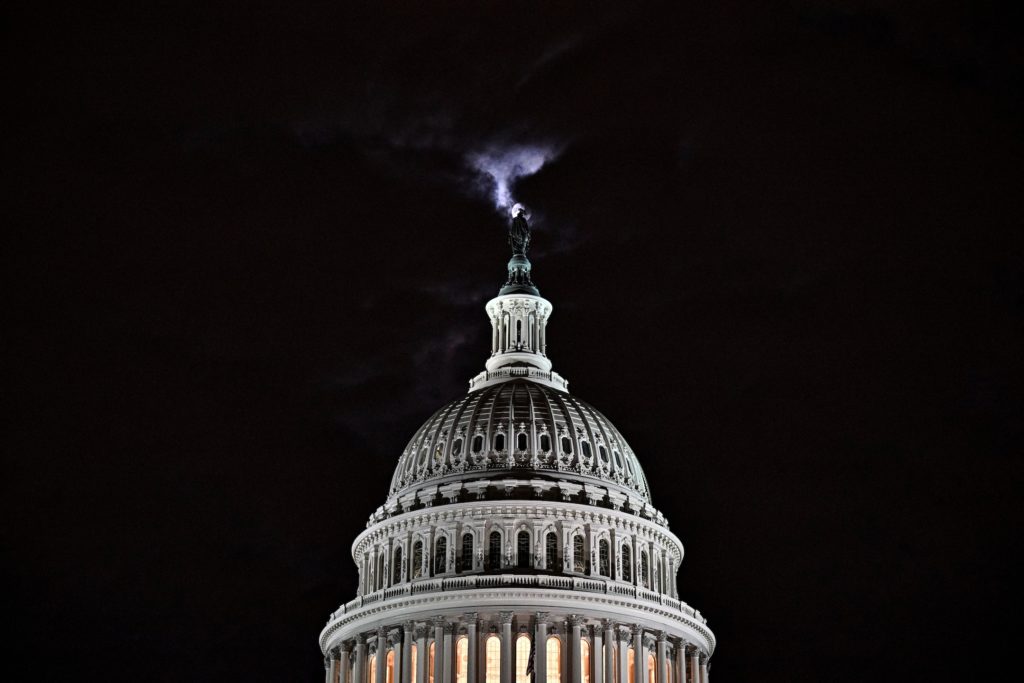 The moon is seen behind the dome of the U.S. Capitol building at night in Washington