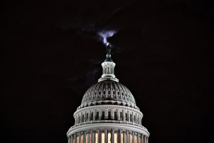 The moon is seen behind the dome of the U.S. Capitol building at night in Washington