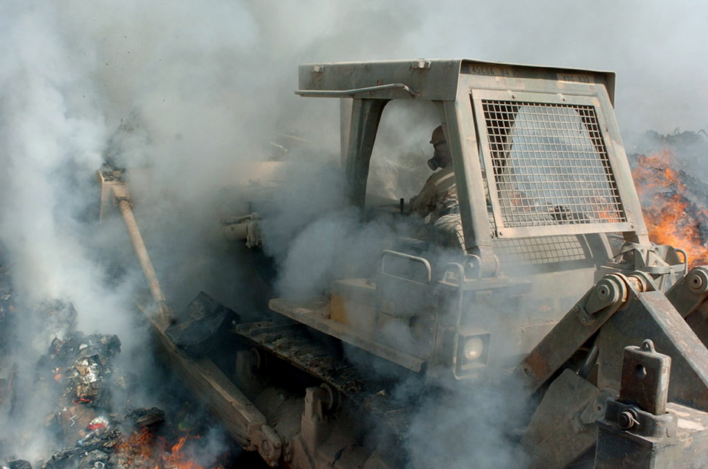 U.S. Army soldiers maneuver items in a burn pit in Iraq