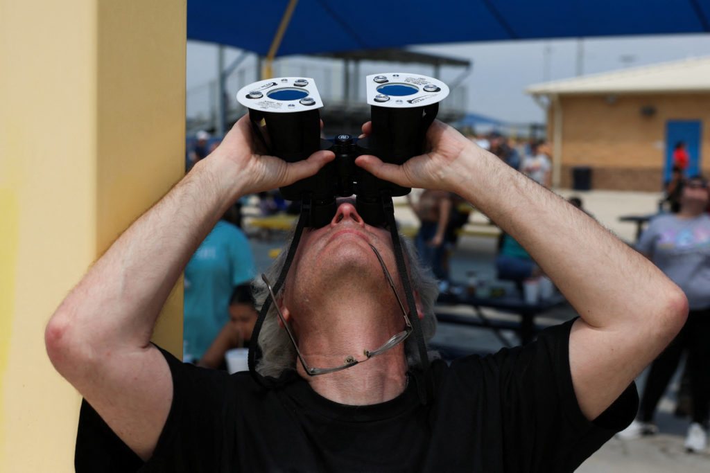 A man looks up as people gather to view a total solar eclipse, where the moon will blot out the sun, in Eagle Pass, Texas, U.S. April 8, 2024. Photo by Christian Monterrosa/Reuters