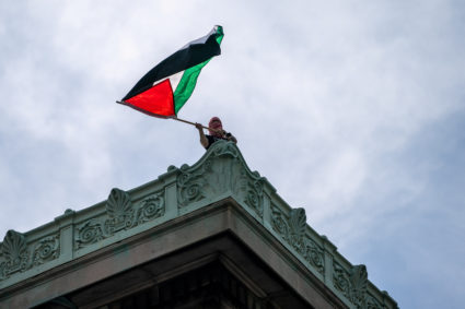 A person waves a Palestinian flag on the rooftop of Hamilton Hall at Columbia University, which student protesters barricaded, despite orders from university officials to disband or face suspension, during the ongoing conflict between Israel and the Palestinian Islamist group Hamas, in New York City, U.S., April 30, 2024. Photo by David Dee Delgado/Reuters