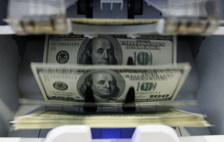 Money counter counts 100 U.S. dollar banknotes in a bank in Bern