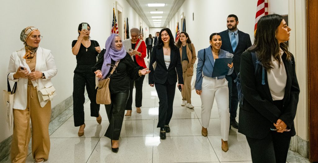 Alt A group of Arab Americans walk down hallway with office doors and American flags during their annual Arab American Advocacy Days in Washington, D.C.