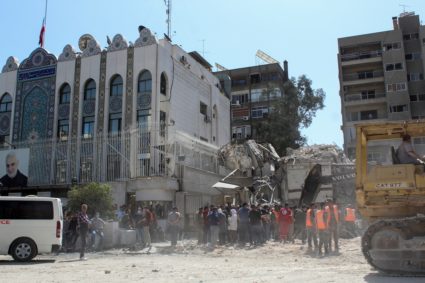 Civil defence members and workers clear rubble after a suspected Israeli strike on Iran's consulate, in Damascus