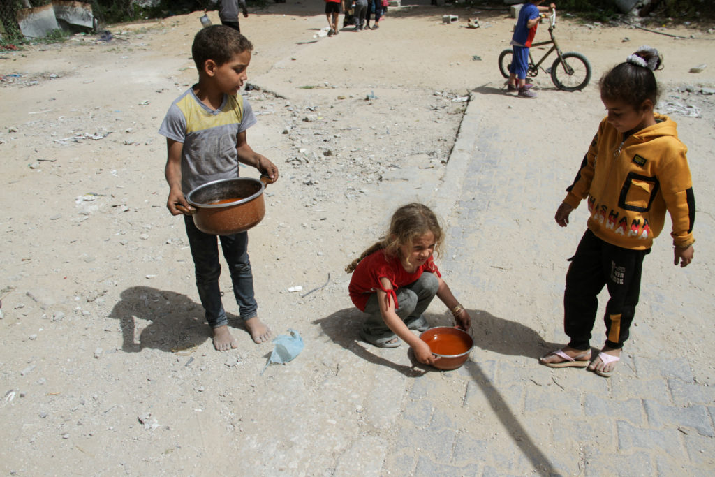 Children hold pots with food, amid the ongoing conflict between Israel and the Palestinian Islamist group Hamas, in Jabalia