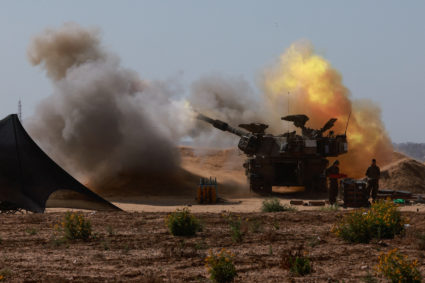 An Israeli military vehicle fires near the Israel-Gaza border, amid the ongoing conflict between Israel and the Palestinia...