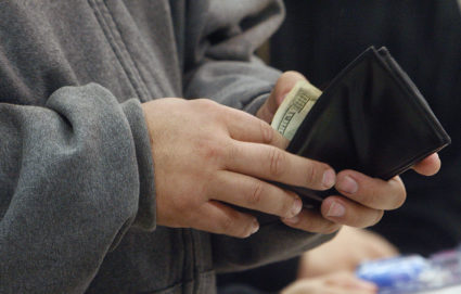 A shopper reaches into his wallet to pay for a purchase on "Black Friday" at the K-Mart store in Burbank, California