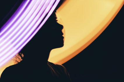 A metaphoric portrait of a human teleporting into a different world with the help of an AI, illuminated by the portal glow...