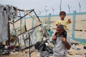 Palestinians inspect a tent camp damaged in an Israeli strike during an Israeli military operation, in Rafah