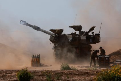 An Israeli military vehicle fires near the Israel-Gaza border, amid the ongoing conflict between Israel and the Palestinia...