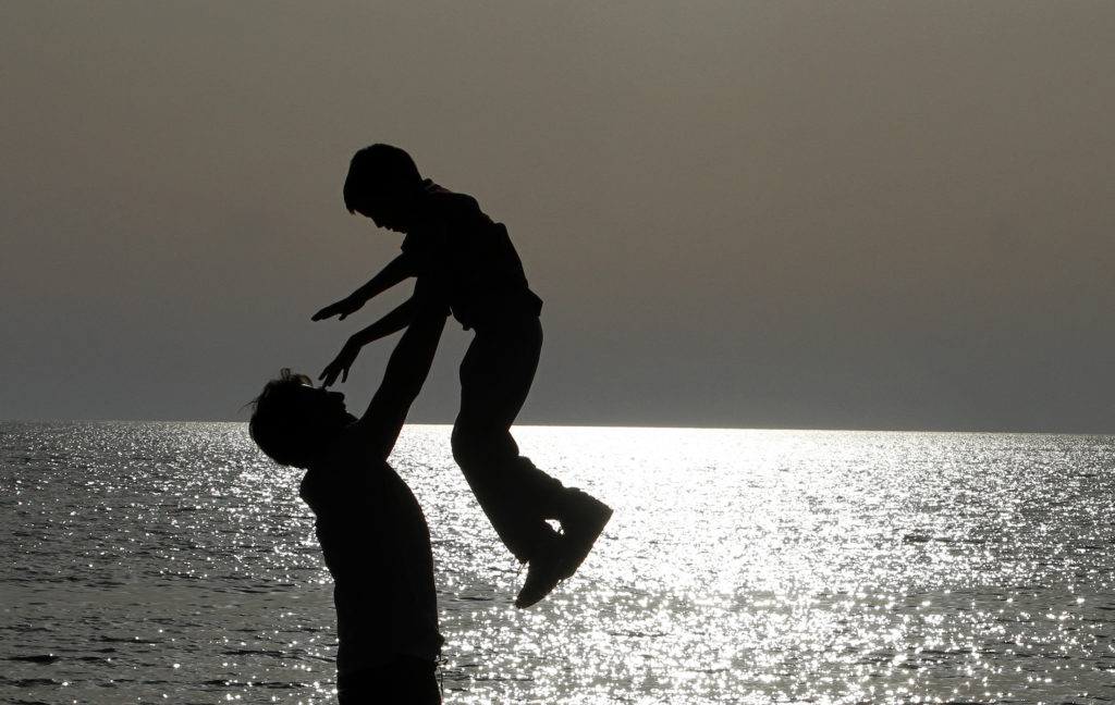 A father plays with his son on a beach facing the Adriatic sea