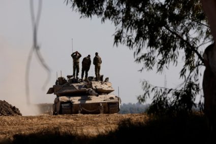 Israeli soldiers stand on top of a tank, near the Israel-Gaza border
