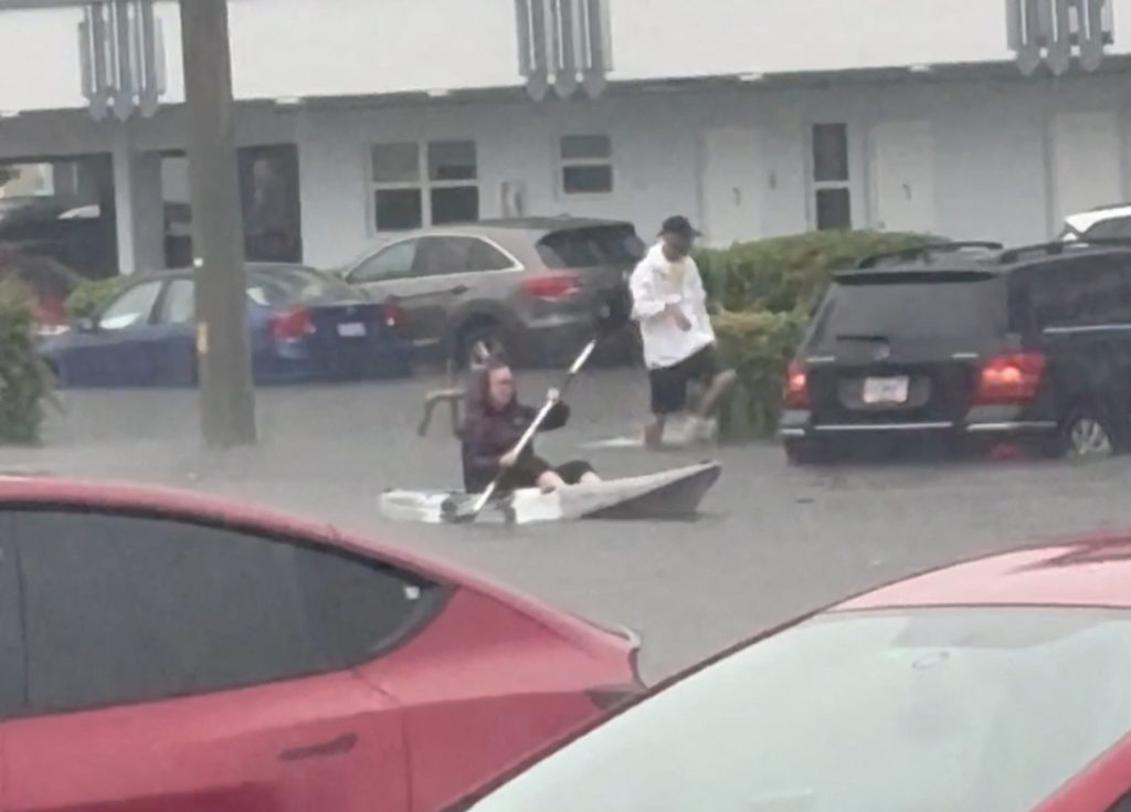 A person rides on a canoe through a flooded street in Hallandale Beach, Florida