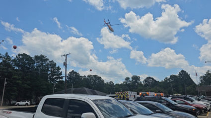 A helicopter flies as emergency vehicles are seen near the scene of a shooting incident in Fordyce