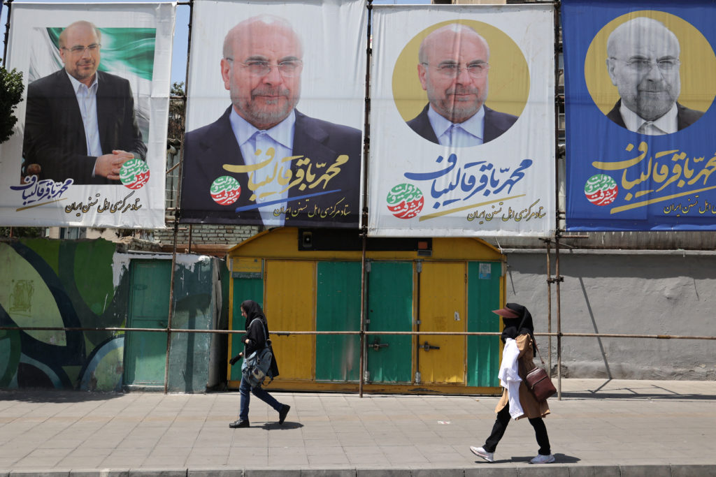 People walk past banners of presidential candidate Mohammad Bagher Ghalibaf displayed in Tehran