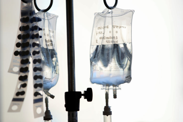 Intravenous bags hang above young cancer patients at Rady's Children Hospital as they participate in decorating golden cap...