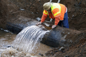 A Los Angeles Department of Water and Power worker looks at the source of a major water main break on Sunset Boulevard in ...