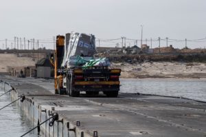 FILE PHOTO: Trucks deliver humanitarian aid over a temporary pier on the Gaza coast