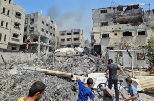 Palestinians inspect a house hit in an Israeli strike, due to an Israeli military operation, in Nuseirat refugee camp