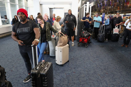 Travelers line up at Milwaukee General Mitchell International Airport due to a worldwide tech outage caused by an update t...