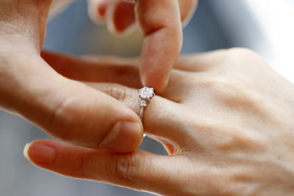A man puts an engagement ring on a woman's finger during a photo opportunity at a jewellery store in Tokyo
