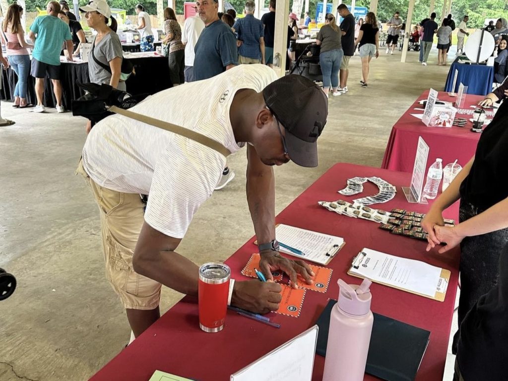 Community member at a Dearborn festival filling out a “Why I Vote” postcard